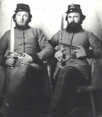 Benjamin Franklin Ammons and Raford Franklin Ammons of the 1st Tennessee Heavy Artillery, C.S.A., seated in uniform holding their weapons. Notice the plaid trousers of the soldier on the right.