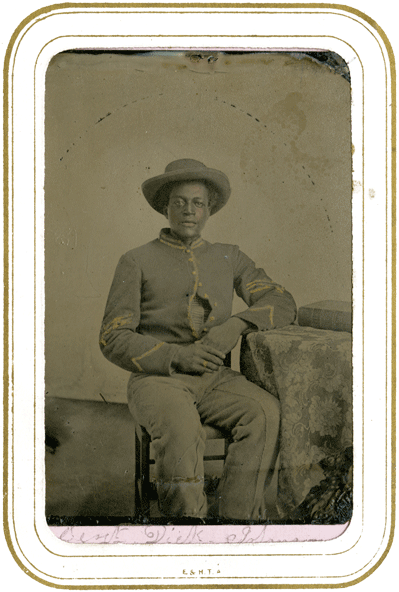 Civil War soldier posing in uniform. Circa 1865. The soldier appears to be african american and has distinct regiment markings.